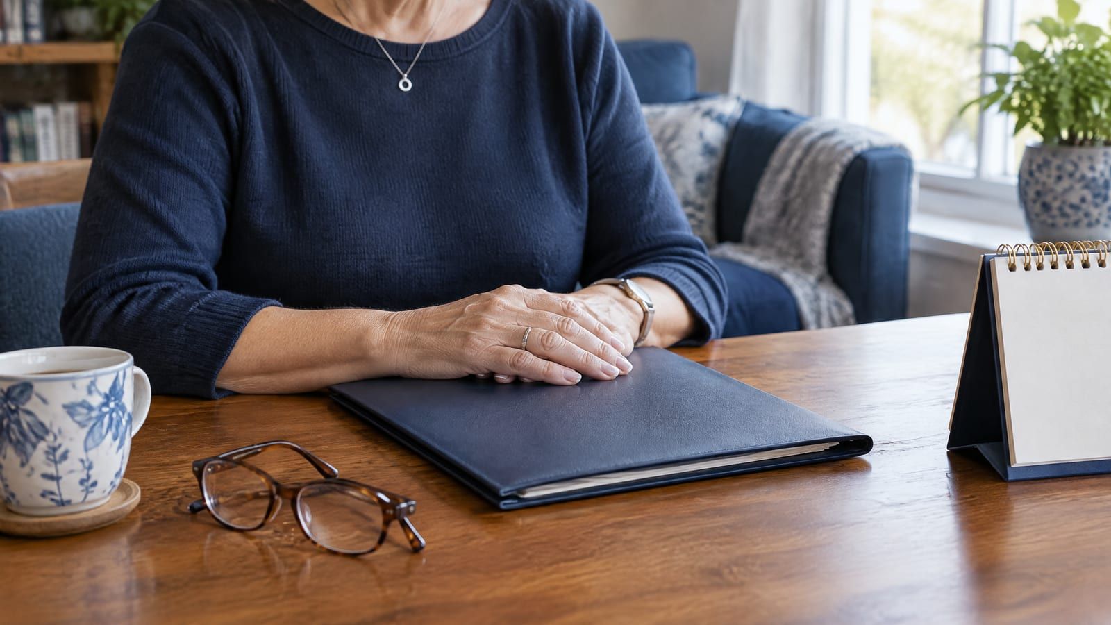 Aposentadoria por idade em 2026: mulher de cerca de 62 anos com pasta de documentos e calendário de mesa junto à janela da sala