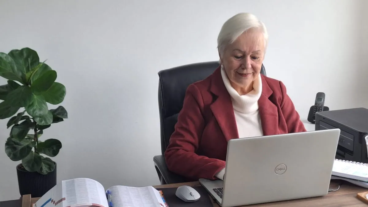 Aposentadoria por tempo de contribuição: a advogada Soeli Konell ao notebook no escritório, com um livro de legislação aberto sobre a mesa