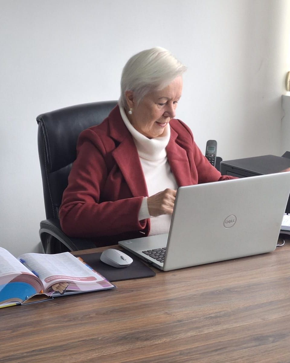 Dra. Soeli Konell à mesa do escritório, com o Vade Mecum aberto e o notebook