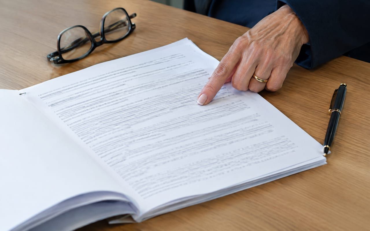 Contrato do plano impresso e grampeado ao lado de óculos de leitura, conferido cláusula por cláusula