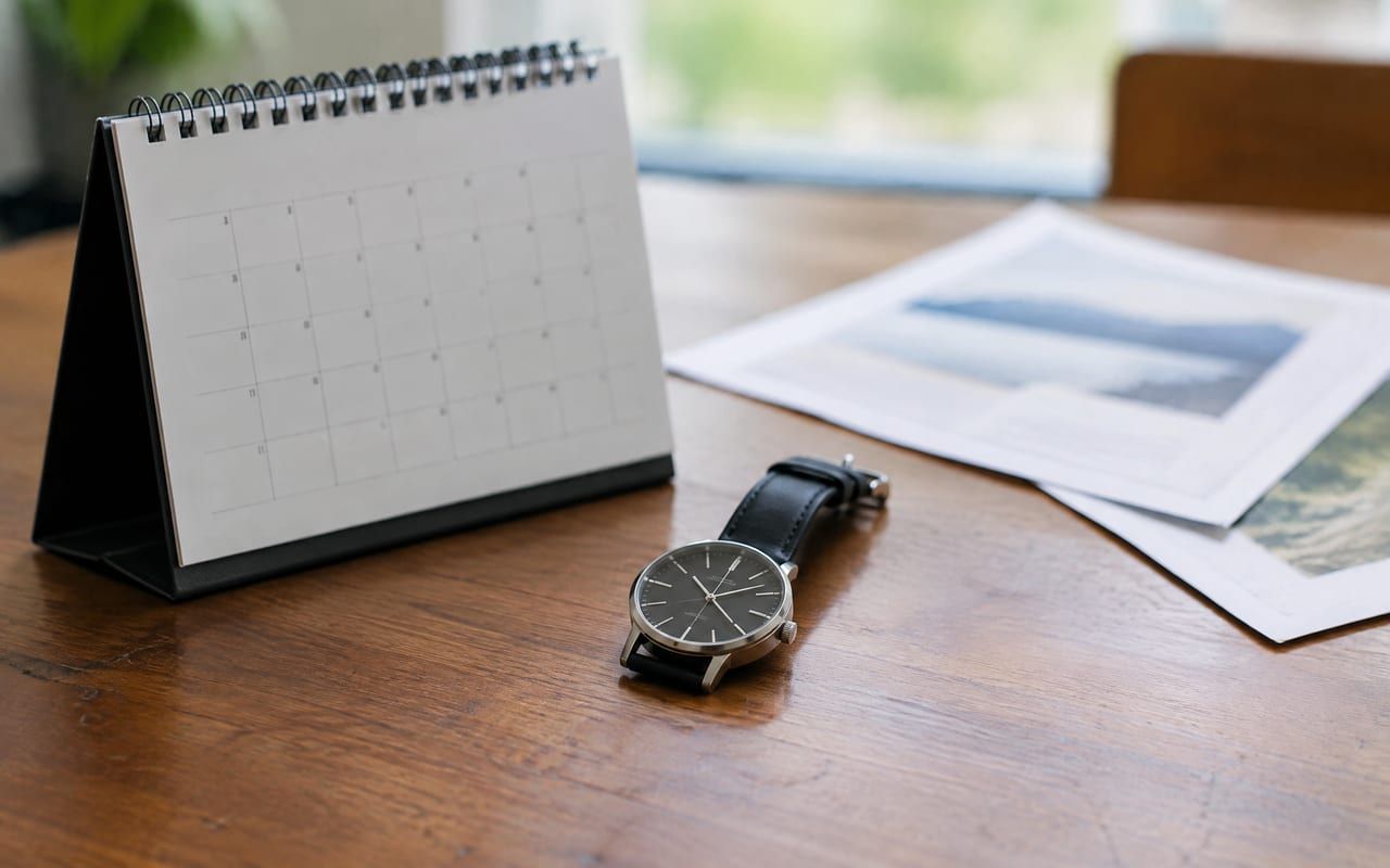 Calendário de mesa e relógio de pulso ao lado de documentos, lembrando os prazos do tratamento