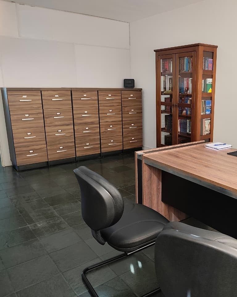 Gaveteiros de arquivo, estante de livros jurídicos e mesa de atendimento no escritório da Dra. Soeli Konell, no Centro de Joinville